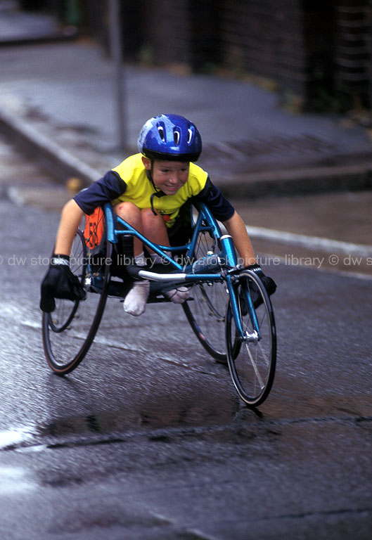 stock photo image: Australia, people, child, children, disabled children, disabled child, boy, boys, male, males, outdoors, disabled, disability, disabilities, disabled people, medical equipment, wheelchair, wheelchairs, athlete, helmet, helmets, athletes, disabled sports, competition, competitions, compete, competing, paraplegic, paraplegics, road, roads, sealed road, sealed roads, handicapped, handicapped people.